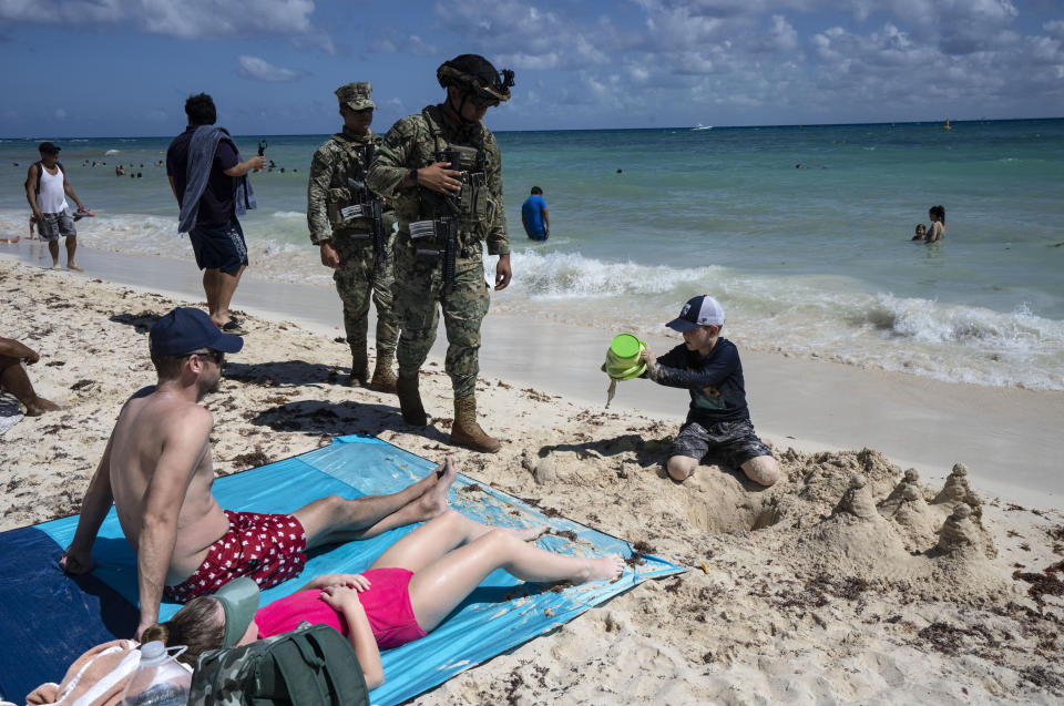 Mexican marines patrol past tourists on the beach in Playa del Carmen, Mexico, Saturday, March 2, 2024. Once a Mayan settlement, the city is among many in the Yucatan Peninsula that in recent decades have been converted into a party hub for vacationing foreigners. (AP Photo/Rodrigo Abd)