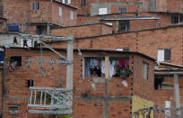 A resident is framed by laundry hanging out to dry in the Paraisopolis favela, during the community's centennial celebration, in Sao Paulo, Brazil, Thursday, Sept. 16, 2021. One of the largest favela's in Brazil, home to tens of thousands of residents in the country's largest and wealthiest city, Paraisopolis is grappling with crime and a pandemic that have challenged daily life for many who live there, but organizers say its people have built a vibrant community and are launching a 10-day celebration of its achievements. (AP Photo/Andre Penner)