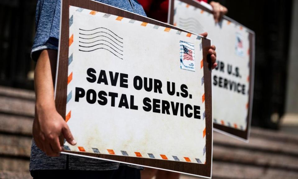 Protesters hold placards during a press conference in front of the post office, in Pasadena, California.