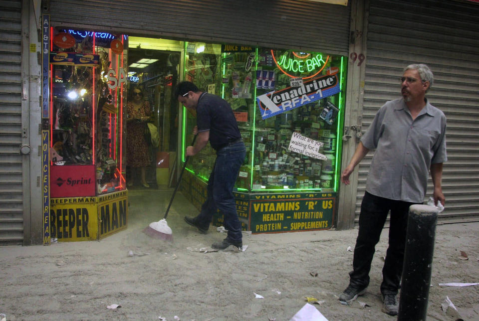 <p>Harry Shasho sweeps up before being evacuated from his vitamin store after the collapse of New York's World Trade Center on Tuesday, Sept. 11, 2001. (AP Photo/Suzanne Plunkett)</p> 