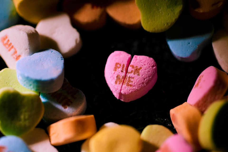 Un acercamiento a un corazón rosa de dulce en el que se lee: “Elígeme” y que está partido a la mitad. (Shirley Yu/The New York Times)