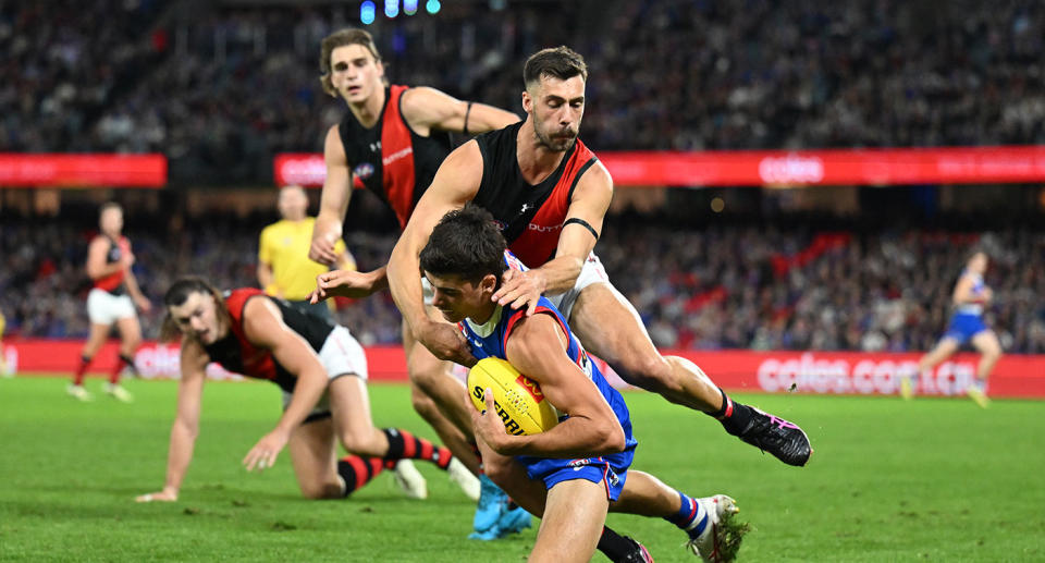 This image shows Essendon's Kyle Langford making a tackle against the Western Bulldogs in the AFL.