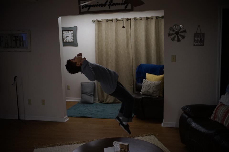 A teen does a backflip inside a living space.