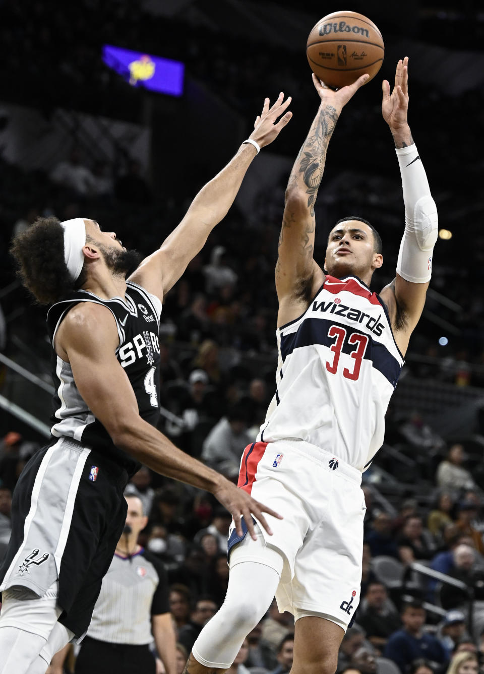 Washington Wizards' Kyle Kuzma (33) shoots against San Antonio Spurs' Derrick White during the first half of an NBA basketball game, Monday, Nov. 29, 2021, in San Antonio. (AP Photo/Darren Abate)