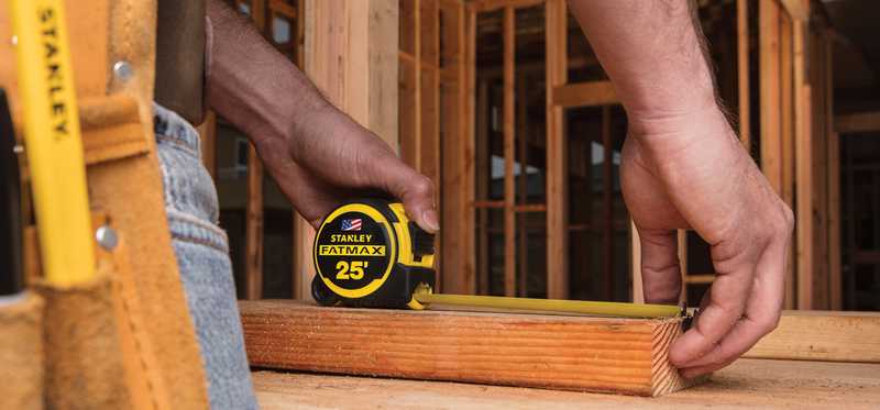 Construction worker using a Stanley Fatmax tape measure on the job.