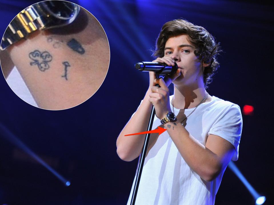 An arrow pointing to a group of tattoos on Harry Styles' wrist.