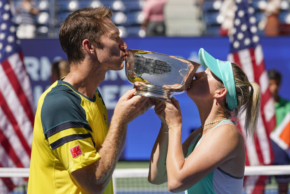 John Peers, left, and Storm Sanders, of Australia, kiss the championship trophy after winning the mixed doubles final against Kirsten Flipkens, of Belgium, and Edouard Roger-Vasselin, of France, at the U.S. Open tennis championships, Saturday, Sept. 10, 2022, in New York. (AP Photo/Matt Rourke)