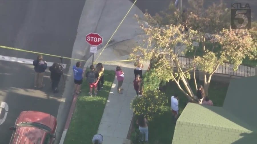 Bystanders watch from behind police tape after a man was fatally shot in Long Beach's MacArthur Park on April 17, 2024. (KTLA)