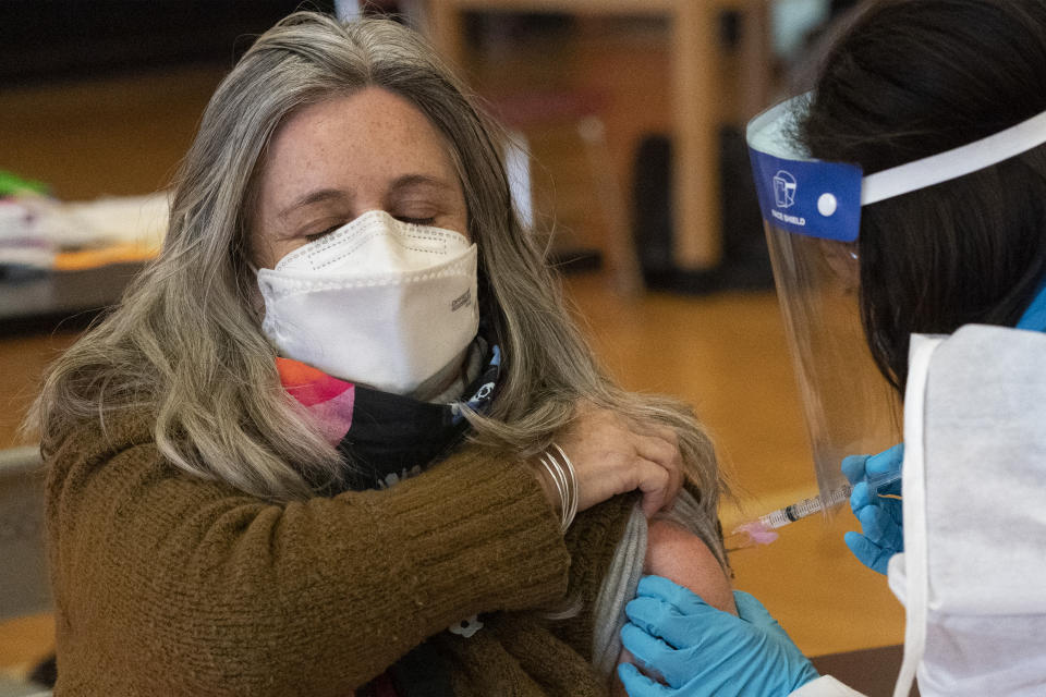 Teacher Lisa Egan is vaccinated with the Moderna coronavirus vaccine at a clinic organized by New York City's Department of Health, Monday, Jan. 11, 2021. "I feel so great, so lucky," she said. "I've been teaching remotely. I'm hoping now I can go back to the classroom." Monday was the first day that people over 75 and essential workers — including police officers, firefighters, and teachers — were allowed to receive the vaccines in New York. (AP Photo/Mark Lennihan)