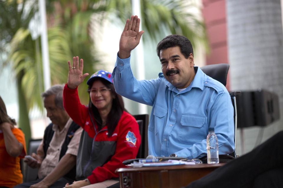 CORRECTS SPELLING OF FIRST LADY'S FIRST NAME - Venezuela's President Nicolas Maduro, right, and First Lady Cilia Flores wave to supporters at a pro-government rally with elderly people in Caracas, Venezuela, Sunday, Feb. 23, 2014. Maduro has been scrambling to squash an increasingly militant opposition movement after two weeks of anti-government protests against crime and inflation. (AP Photo/Rodrigo Abd)