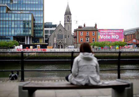 A woman sits in front of a pro-life poster in the city centre of Dublin, Ireland, May 22, 2018. REUTERS/Max Rossi