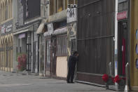 A security guard peers into a store along a stretch of shuttered restaurants in Beijing, Thursday, Nov. 24, 2022. China is expanding lockdowns, including in a central city where factory workers clashed this week with police, as its number of COVID-19 cases hit a daily record. (AP Photo/Ng Han Guan)