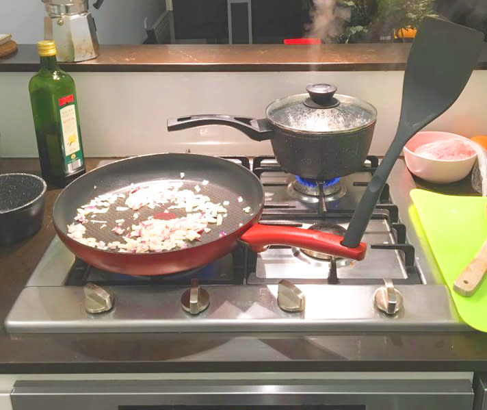 Spatula Hack in red pan on stove cooking onion