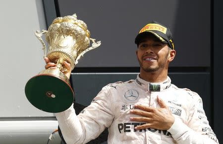 Britain Formula One - F1 - British Grand Prix 2016 - Silverstone, England - 10/7/16 Mercedes' Lewis Hamilton celebrates on the podium with the trophy after winning the race REUTERS/Andrew Boyers Livepic EDITORIAL USE ONLY.