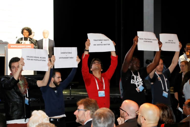 People hold placards during the opening of the 9th International AIDS Society conference on HIV Science on July 23, 2017, in Paris