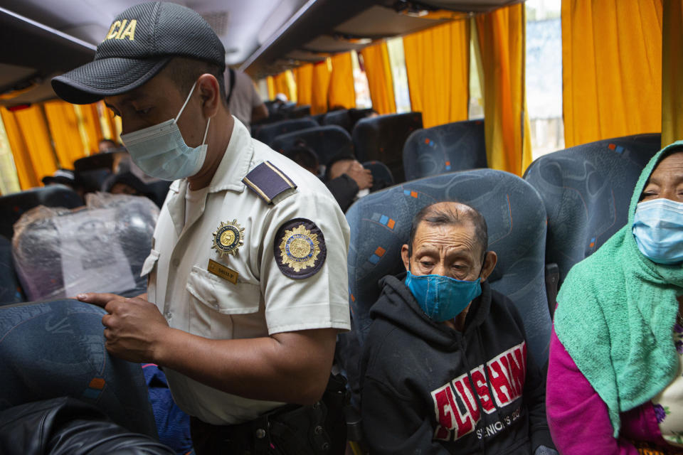 A member of the Guatemalan police in search of Honduran migrants checks the documents of bus passengers in Zacapa, Guatemala, Tuesday, Jan. 19, 2021. A once large caravan of Honduran migrants that pushed its way into Guatemala last week had dissipated by Tuesday in the face of Guatemalan security forces. (AP Photo/Oliver de Ros)