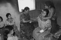 <p>Berta Navichoc heals Marta Mendoza Damian after she fell from a truck on her way to work. (Photograph by Fran Antmann) </p>