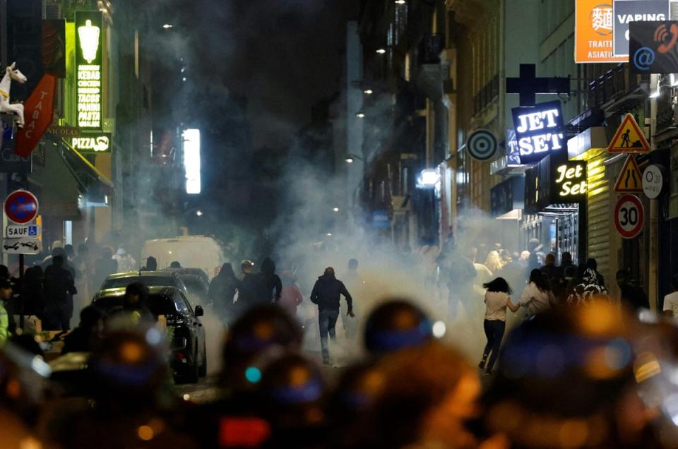 Demonstrators run as French police officers use teargas to disperse riots (AFP via Getty)