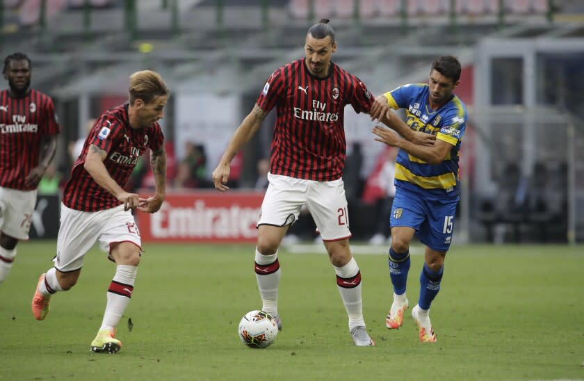 AC Milan's Zlatan Ibrahimovic, centre, fights for the ball with Parma's Gaston Brugman, right, during a Serie A soccer match between AC Milan and Parma, at the San Siro stadium in Milan, Italy, Wednesday, July 15, 2020. (AP Photo/Luca Bruno)