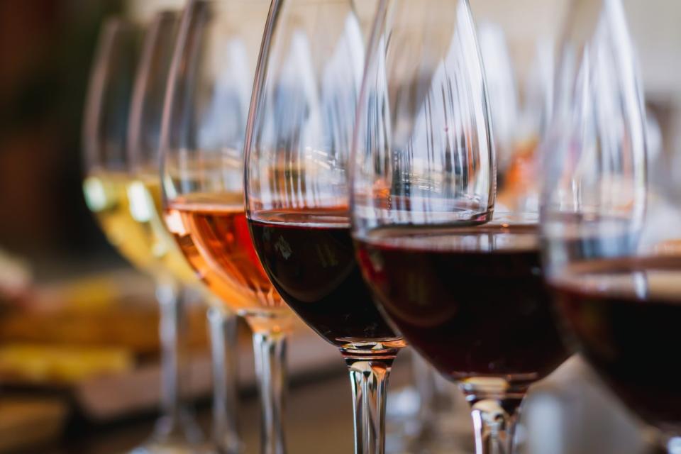 close up of a row of shiny wine glasses with different kinds of wine