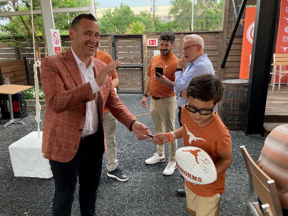 Texas football coach Steve Sarkisian autographs a football for 11-year-old Asher Wilson, who says he's been a Longhorns fan "since the day I was born." Sarkisian and several other Texas coaches talked to fans and boosters at J-Bar-M Barbecue in Houston on Tuesday, which marked the last stop on the annual Texas Fight Tour.