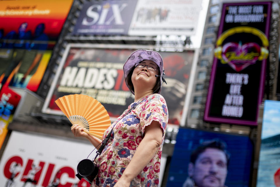 FILE - A tour guide fans herself while working in Times Square as temperatures rise, July 27, 2023, in New York. Nearly 60% of the U.S. population, are under a heat advisory or flood warning or watch as the high temperatures spread and new areas are told to expect severe storms. (AP Photo/John Minchillo, File)