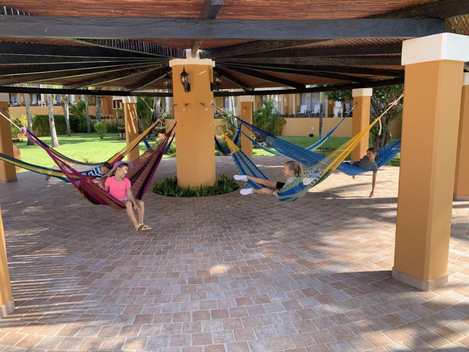 Children sitting on hammocks in a pavilion and talking.