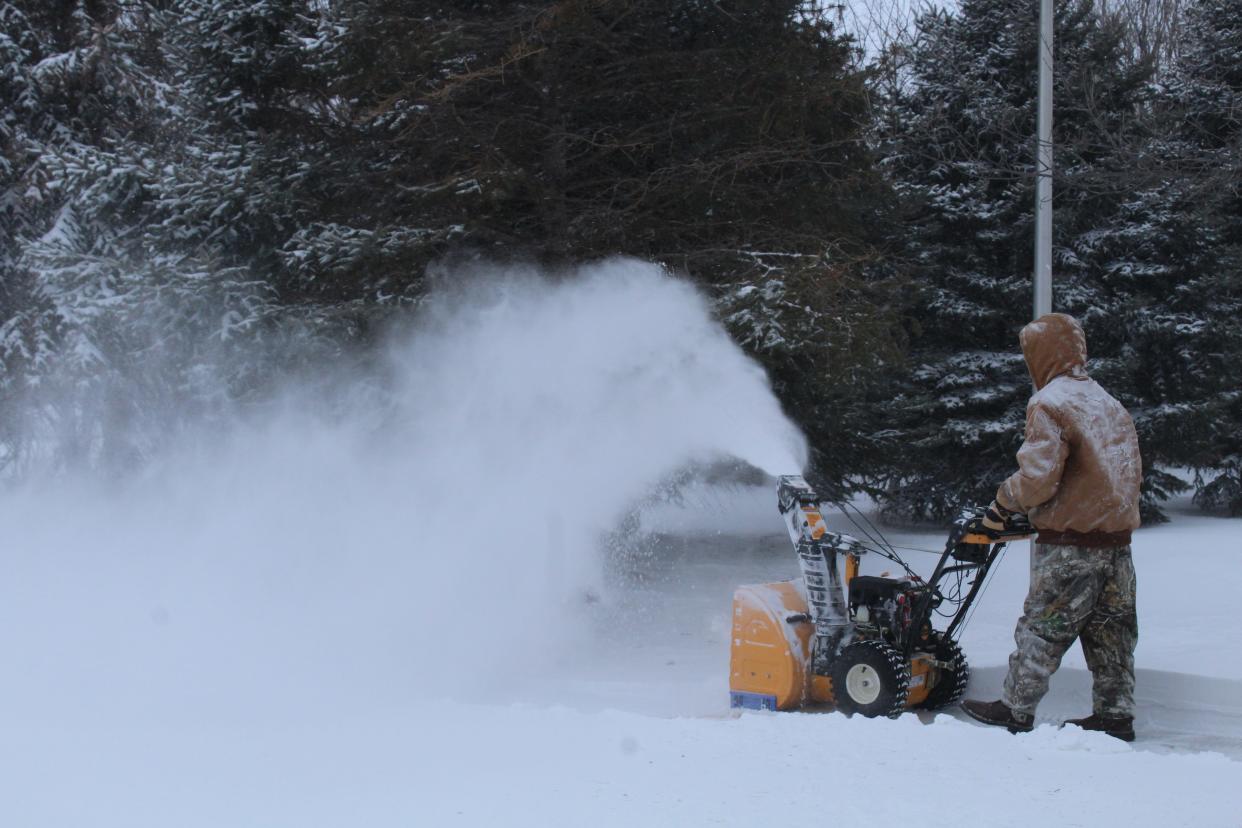 Jayden Biegler uses blows snow from an Aberdeen sidewalk Monday evening.