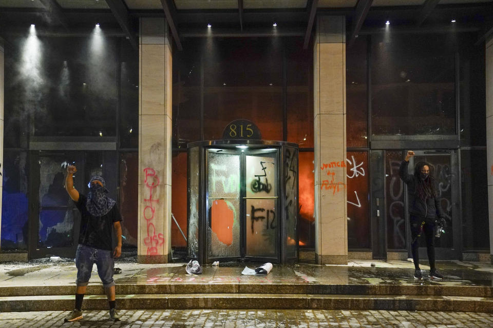 Demonstrators hold their fist in the air while a fire burns inside the AFL-CIO headquarters. (Photo: ASSOCIATED PRESS)