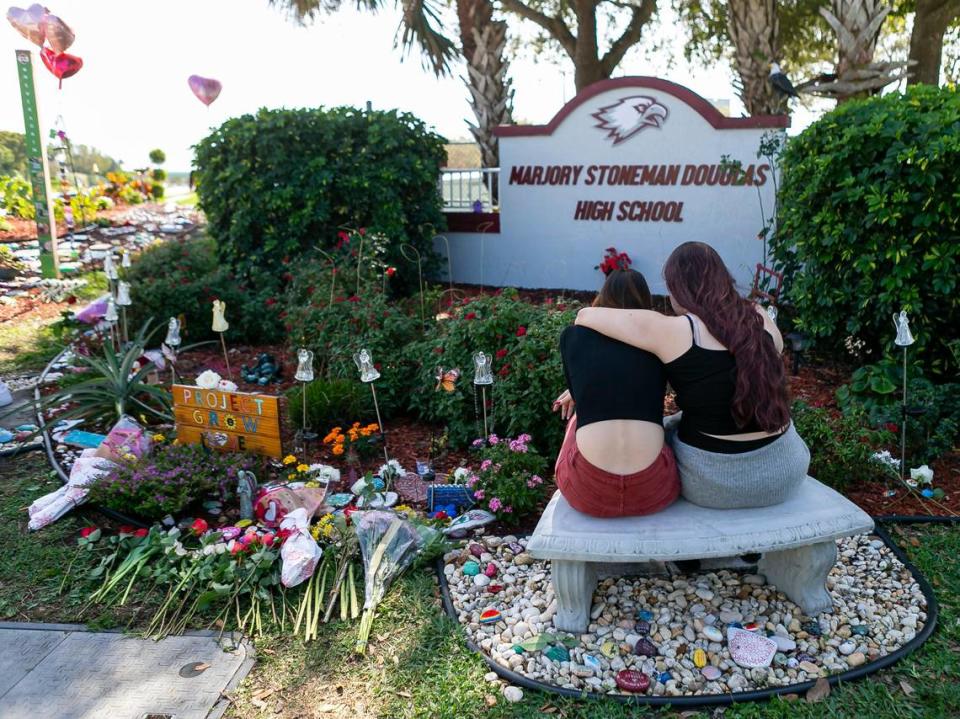 Jess Shanahan, de 17 años, abraza a su amiga Lauryn Augustyne, de 19, mientras visitan un monumento improvisado en el exterior de la secundaria Marjory Stoneman Douglas el viernes 14 de febrero de 2020, en el segundo aniversario del tiroteo de Parkland en el que murieron 17 víctimas.