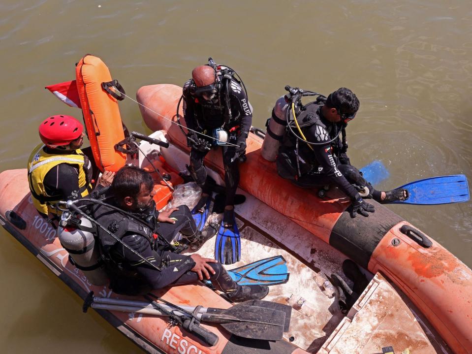 A photo of men in a boat preparing to dive and look for bodies.