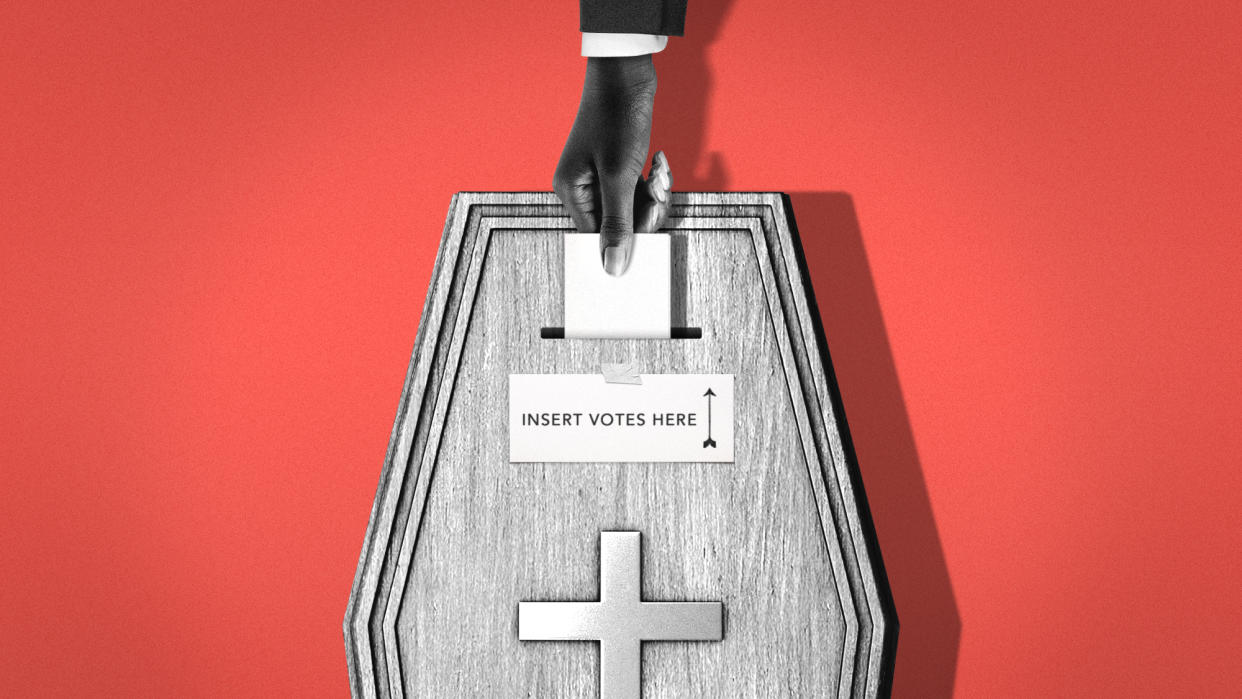  Hand placing vote in a coffin-shaped ballot box. 