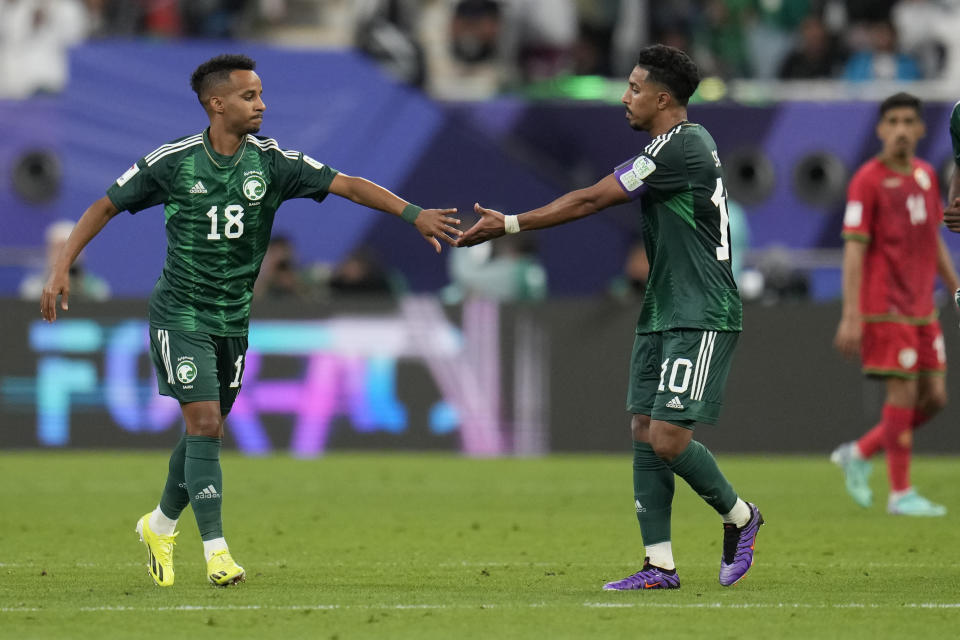 Saudi Arabia's Abdulrahman Ghareeb, left, celebrates with Salem Aldawsari, after scoring his side's first goal, during the Asian Cup Group F soccer match between Saudi Arabia and Oman at Khalifa International Stadium in Doha, Qatar, Tuesday, Jan. 16, 2024. (AP Photo/Aijaz Rahi)