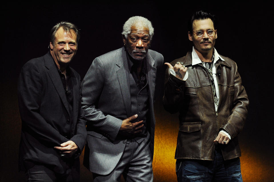 Johnny Depp, right, a cast member in the upcoming film "Transcendence," gestures to fellow cast member Morgan Freeman, center, as the film's director Wally Pfister looks on from the stage during the Warner Bros. presentation at CinemaCon 2014 on Thursday, March 27, 2014, in Las Vegas. (Photo by Chris Pizzello/Invision/AP)