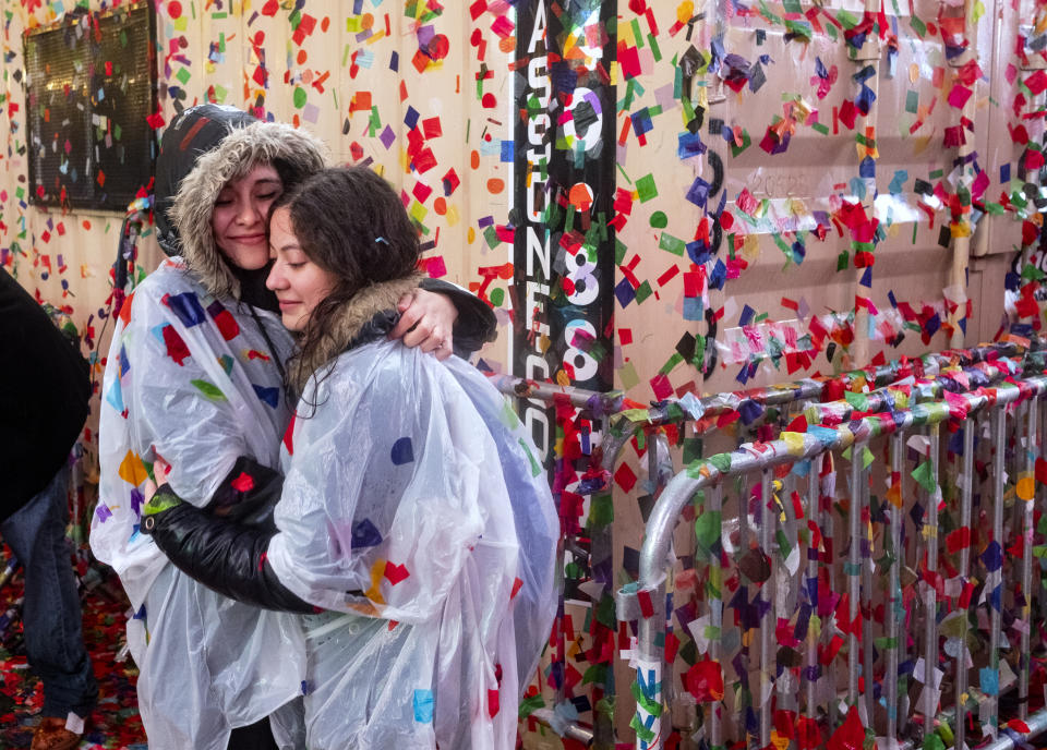 As rain-soaked confetti sticks to most surfaces, revelers embrace in Times Square, early Tuesday, Jan. 1, 2019, as they take part in a New Year's celebration in New York. (AP Photo/Craig Ruttle)