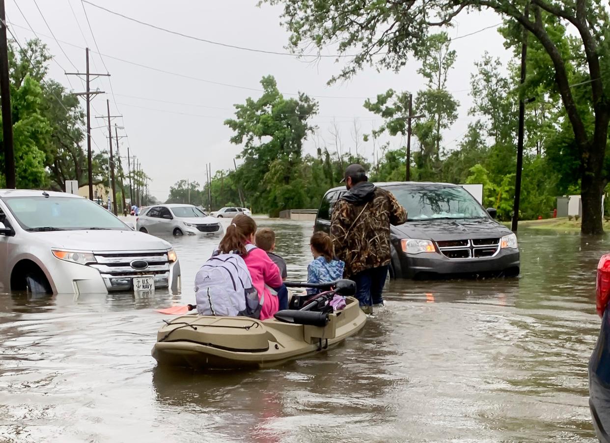 <p>Parents use boats to pick up students from schools after nearly a foot of rain fell in Lake Charles, Louisiana on 17 May.</p> (AP)