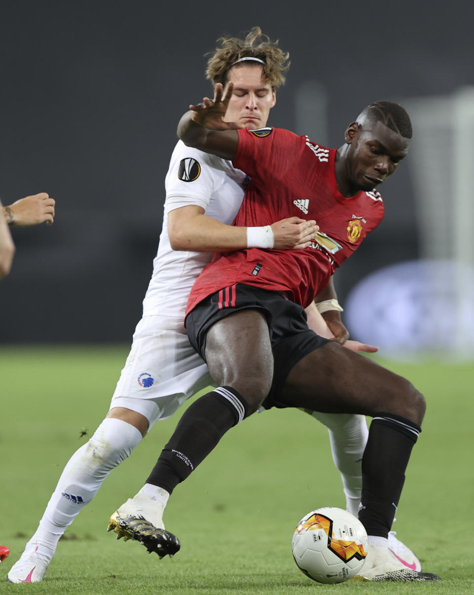 Robert Mudrazija, izquierda, de Copenhaguen, y Paul Pogba, de Manchester United, se disputan el balón en un partido de cuartos de final de la Liga Europa el lunes, 10 de agosto del 2020, en Colonia, Alemania. (Wolfgang Rattay/Pool vía AP)