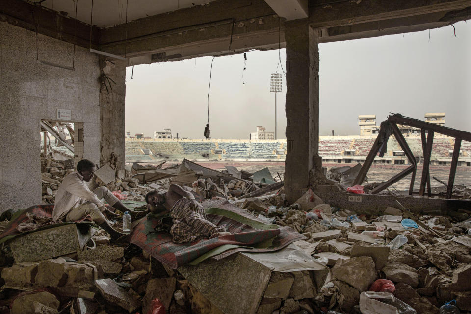 In this July 21, 2019 photo, Ethiopian migrants take shelter in the "22nd May Soccer Stadium," destroyed by war, in Aden, Yemen. Over the summer, the stadium became a temporary refuge for thousands of migrants. At first, security forces used it to house migrants they captured in raids. Other migrants showed up voluntarily, hoping for shelter. The IOM distributed food at the stadium and arranged voluntary repatriation back home for some. The soccer pitch and stands became a field of tents, with clothes lines strung up around them. (AP Photo/Nariman El-Mofty)