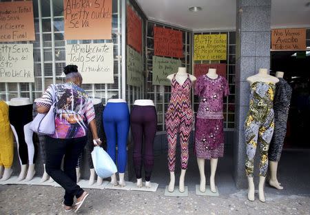 A woman walks past clothes for sale and signs reading "Closing down sale" in Arecibo, Puerto Rico, June 29, 2015. REUTERS/Alvin Baez-Hernandez