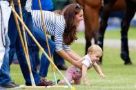 <p>Duchess Kate plays with baby Prince George in the grass while they watch Prince William play in a charity polo match.</p>