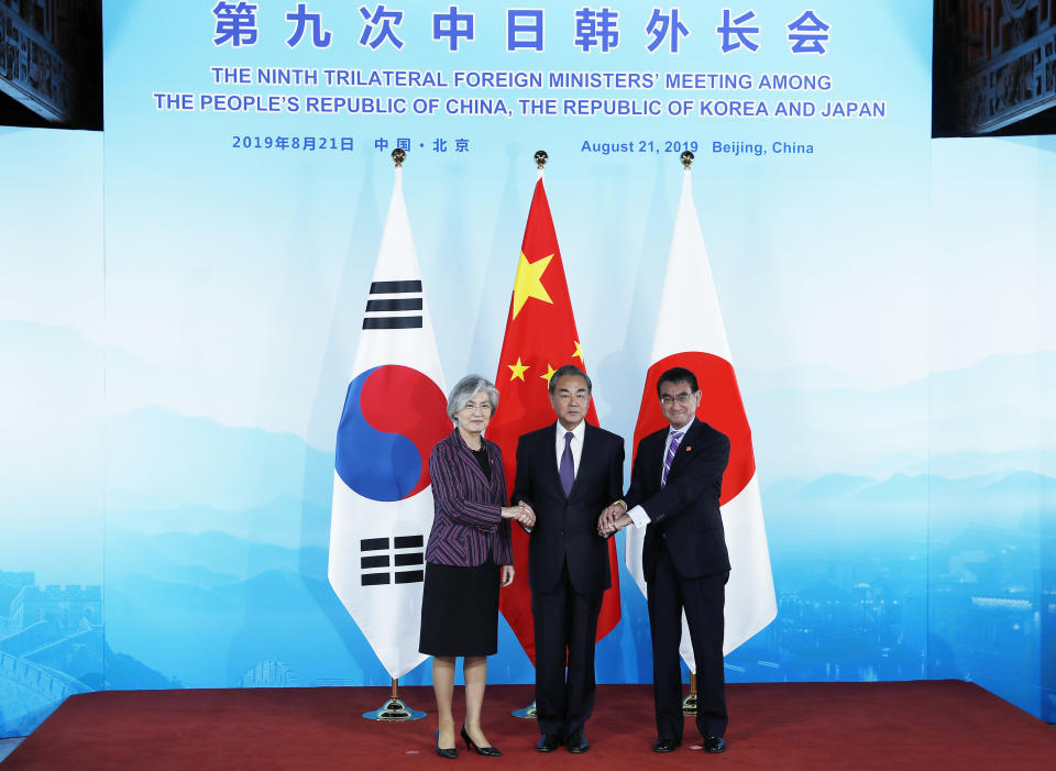 Chinese Foreign Minister Wang Yi, center, holds hands of his South Korean counterpart Kang Kyung-wha, left, and Japanese counterpart Taro Kono ahead of their trilateral meeting at Gubei Town in Beijing Wednesday Aug. 21, 2019. (Wu Hong/Pool Photo via AP)