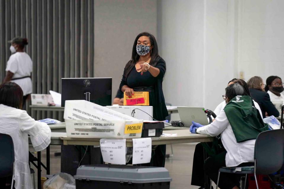 A supervisor distributes absentee ballots to be counted by election workers inside Hall E of Huntington Place in downtown Detroit on Tuesday, August 2, 2022.