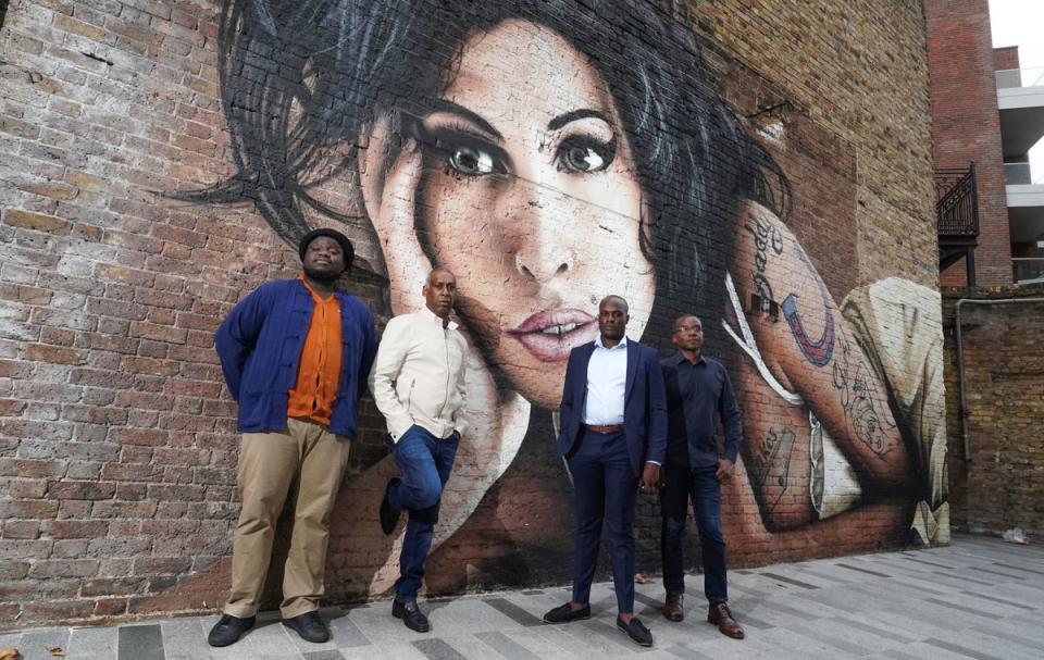 Amy Winehouse’s band pose with her mural behind The Hawley Arms (PA)