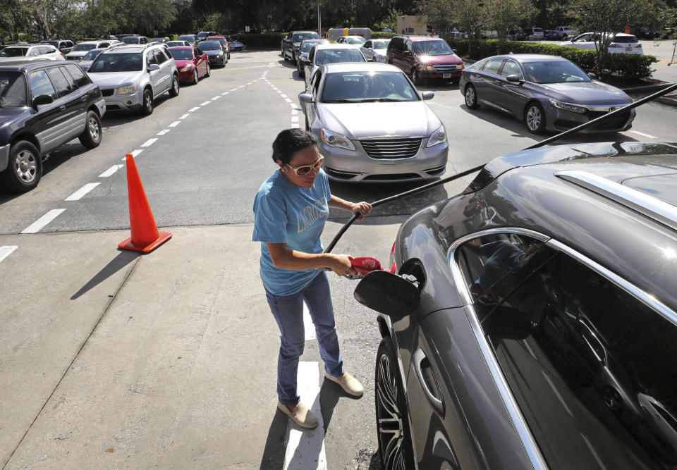 A customer fills up her tank as others wait in line for gas at a Costco store in Altamonte Springs, Fla., Friday, Aug. 30, 2019, as central Florida residents prepare for a possible strike by Hurricane Dorian. (Joe Burbank/Orlando Sentinel via AP)