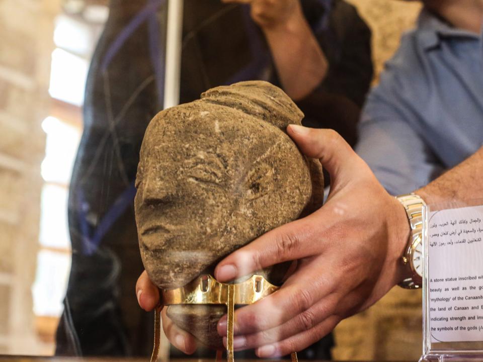 Palestinian archaeologist displays a stone statue carved with the face of Canaanite goddess Anat.