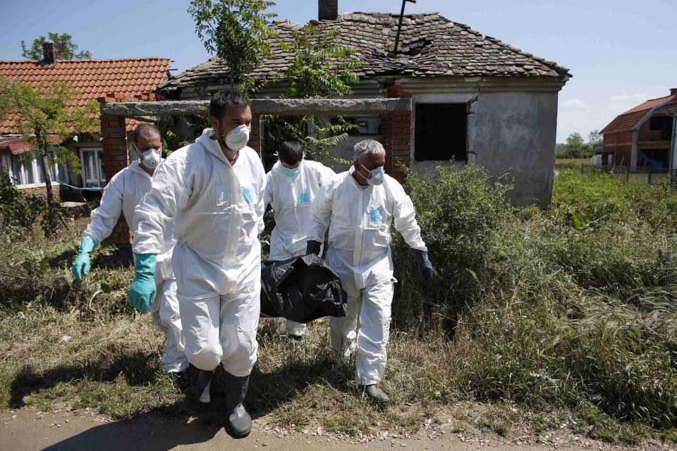 Serbian forensic specialists remove a body in front of a flooded house in Obrenovac