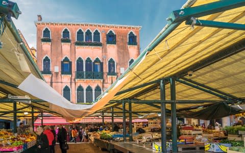 Shoppers looking around Rialto Market, Venice - Credit: Getty