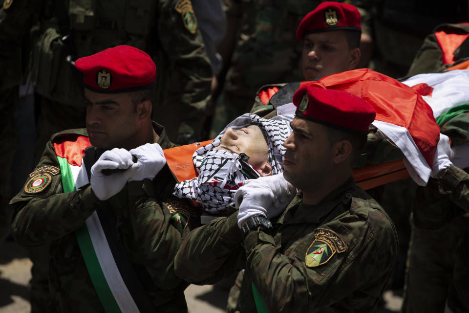 Palestinian security officers carry the body of a their colleague, Tayseer Issa, in the West Bank city of Jenin, Thursday, June 10, 2021. Israeli troops shot and killed three Palestinians, including two security officers, in a shootout that erupted in the West Bank town of Jenin during what appeared to be an Israeli arrest raid overnight, Palestinian officials said Thursday. (AP Photo/Majdi Mohammed)