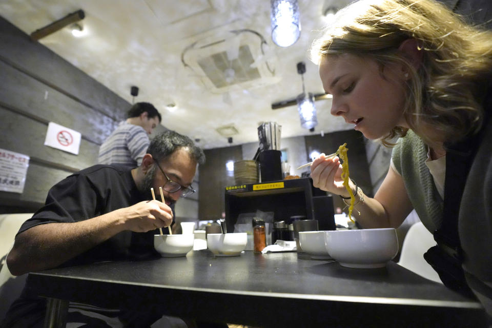 Participants eat the noodle at Shinbusakiya, a ramen shop which offers "Hokkaido classics," during Tokyo Ramen Tours at Shibuya district on April 2, 2024, in Tokyo. (AP Photo/Eugene Hoshiko)