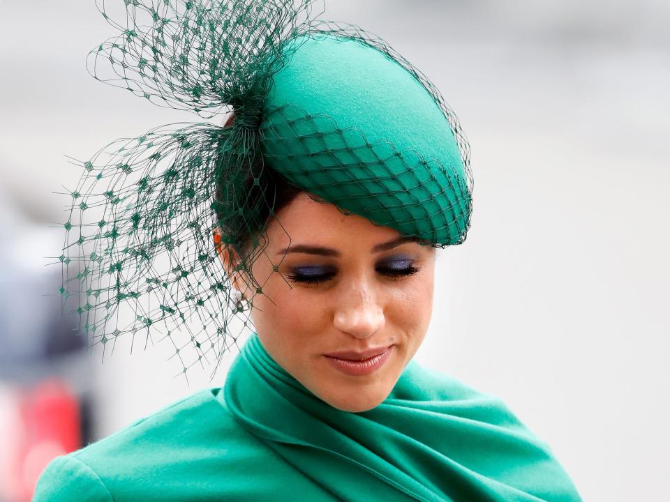 Meghan Markle wearing a green dress and hat looking down